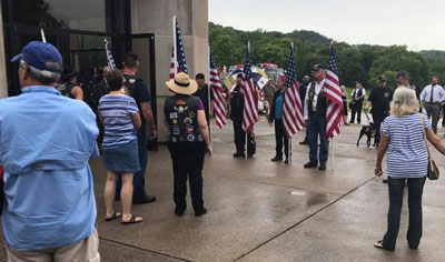 Photo of the Members of the Patriot Guard saluting a departed veteran with US Flags.